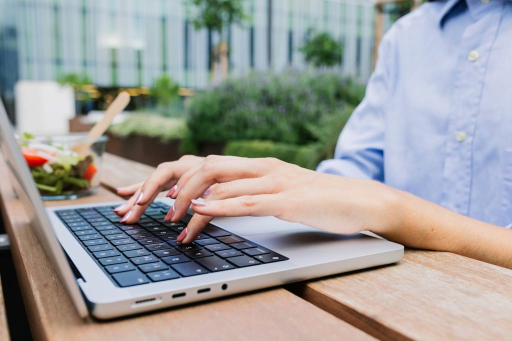 Close up of female student hands typing on laptop sitting at campus college