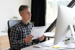 Professional Man Reviewing Documents at Modern Office Desk