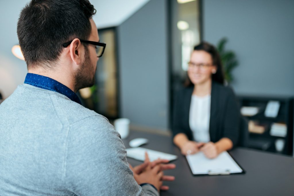 Young male worker being interviewed for a job by a women.